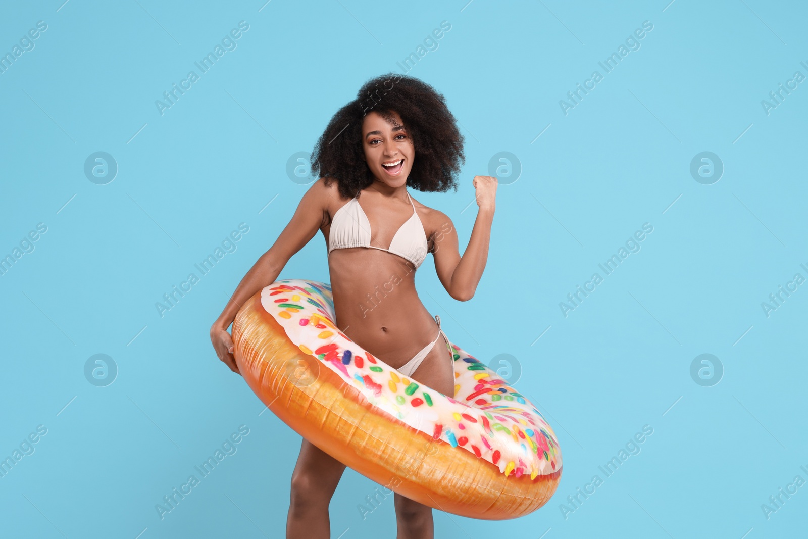 Photo of Beautiful woman in stylish bikini with inflatable ring on light blue background