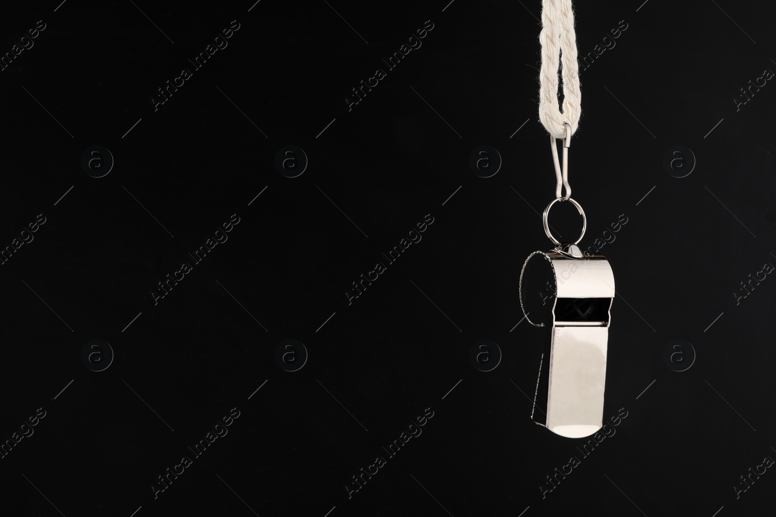 Photo of Referee equipment. Metal whistle on black background, closeup and space for text