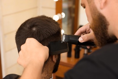 Photo of Professional hairdresser working with client in barbershop, closeup