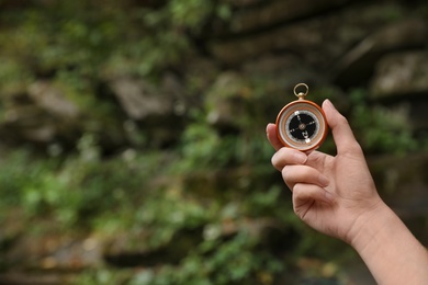 Photo of Traveler searching direction with compass in wilderness, closeup. Space for text