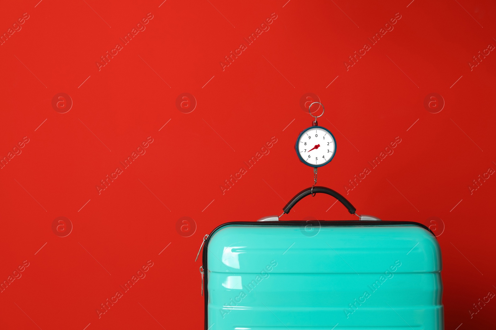 Photo of Modern suitcase and hanging scales against color background, space for text