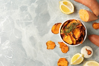 Flat lay composition with sweet potato chips on grey table. Space for text