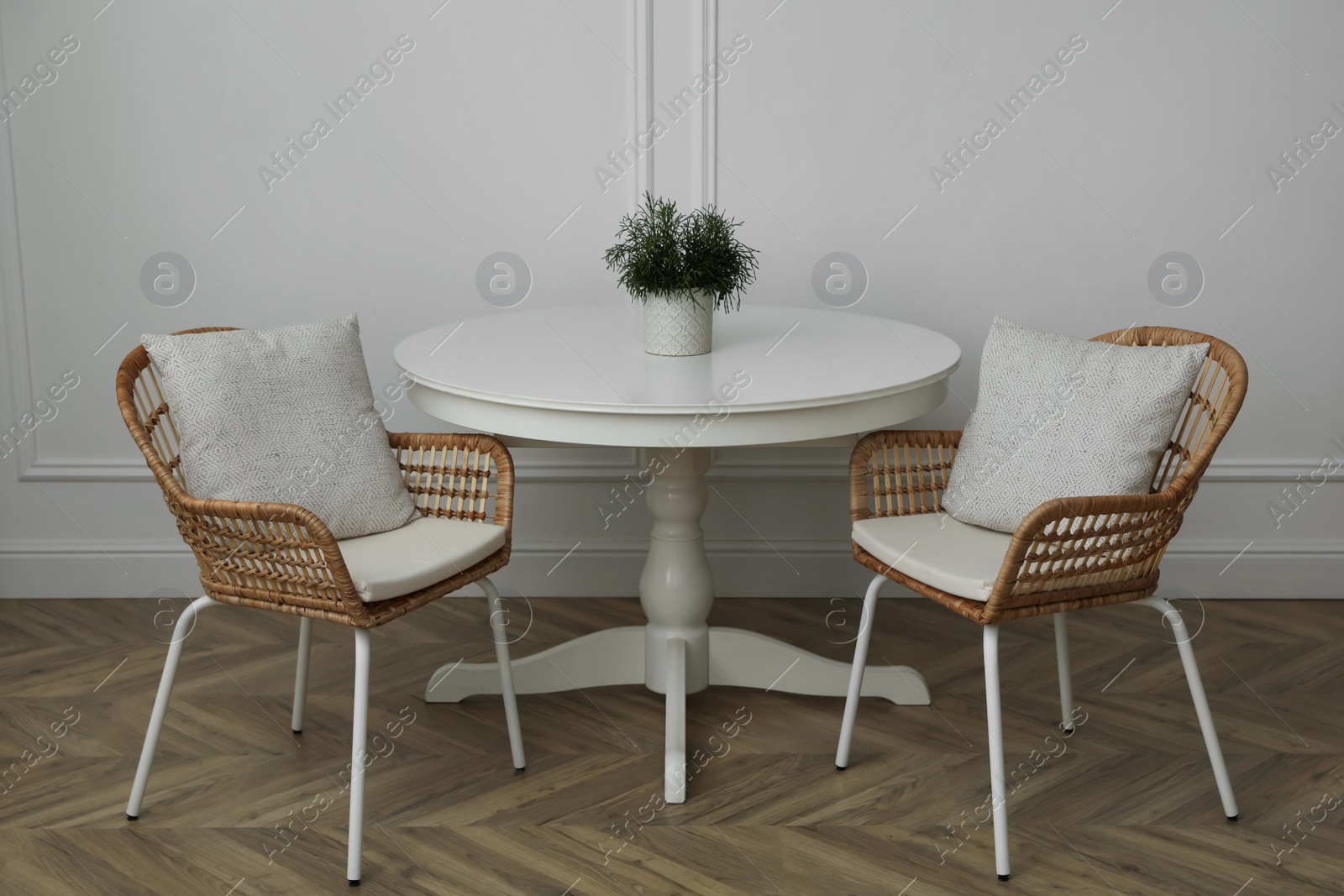 Photo of Round table and wicker armchairs near white wall in room