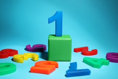 Photo of Number One among fallen magnets on light blue background