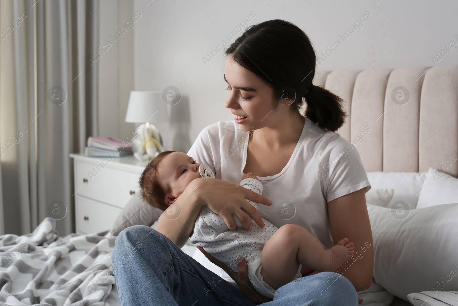 Photo of Young woman with her little baby on bed at home