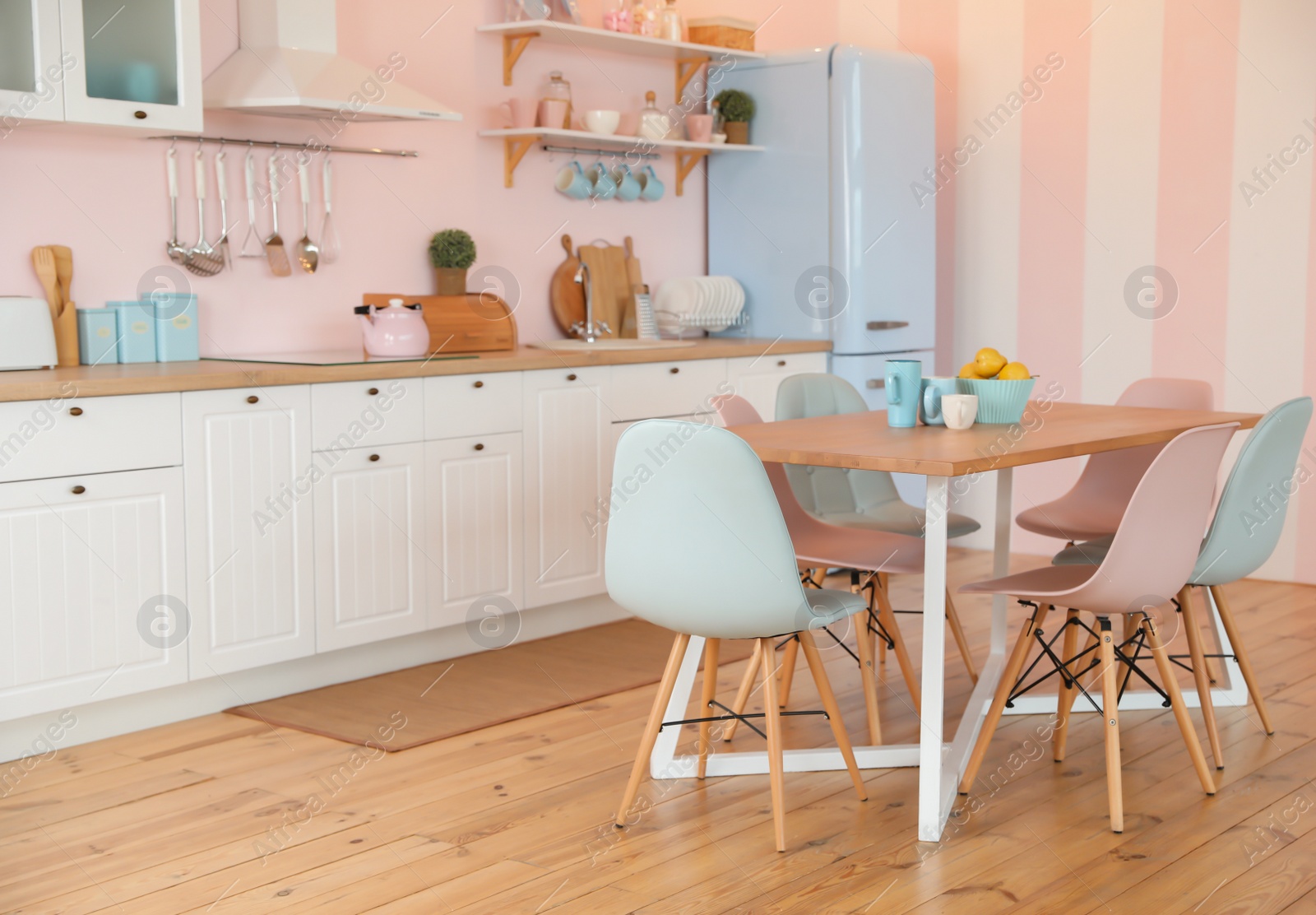 Photo of Stylish pink kitchen interior with dining table and chairs