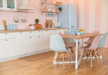 Stylish pink kitchen interior with dining table and chairs