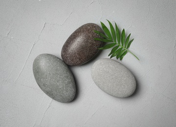 Spa stones and green leaf on grey table, flat lay