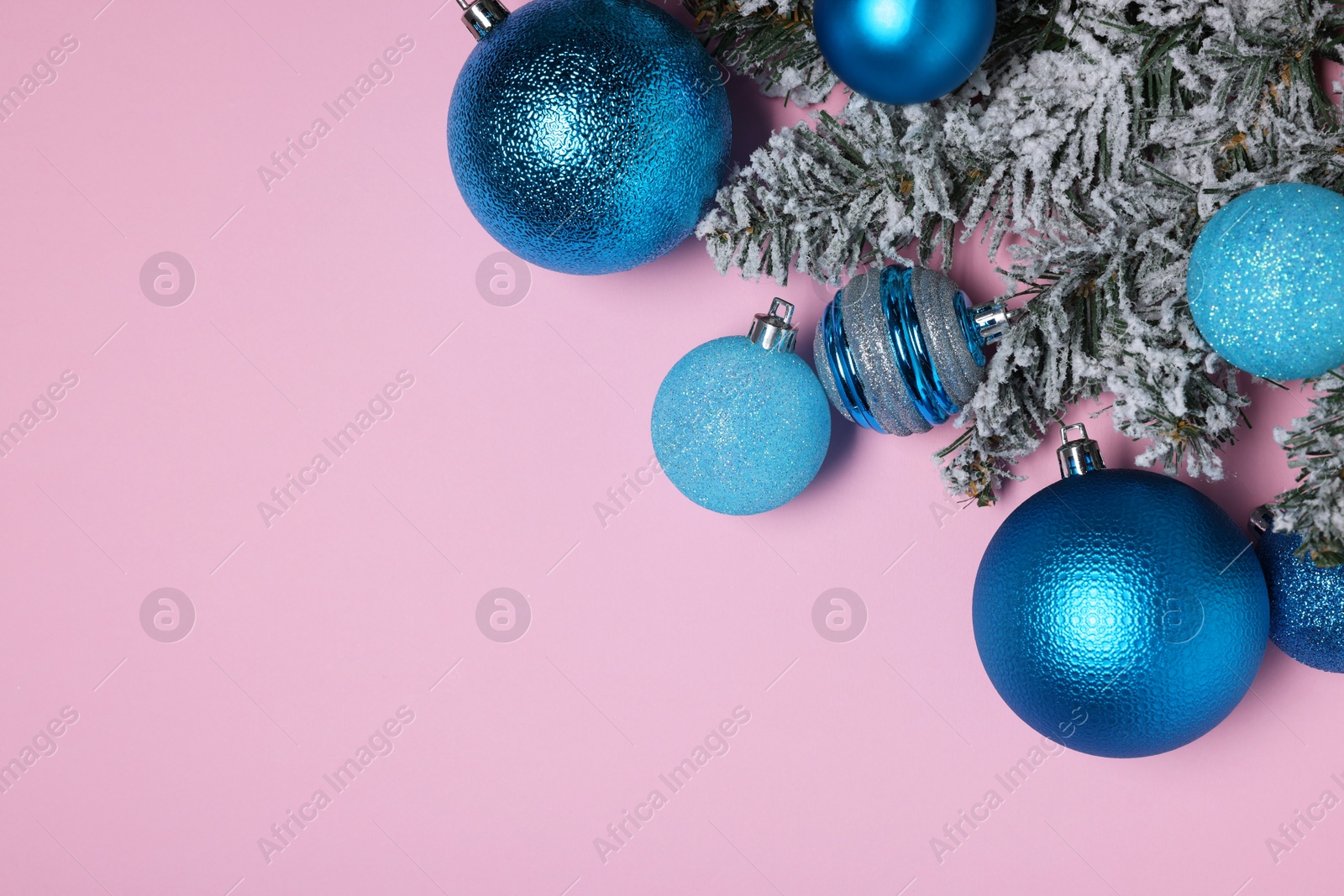 Photo of Shiny blue Christmas balls and fir tree branches with snow on pink background, flat lay. Space for text
