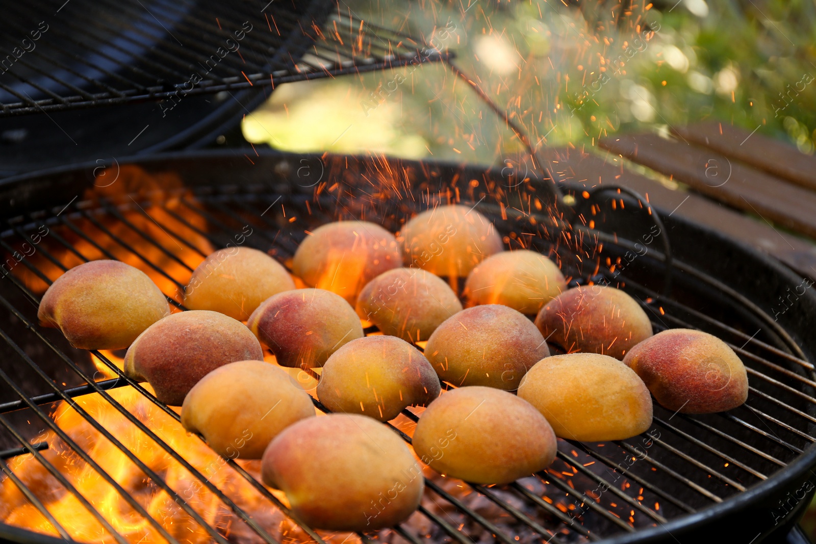 Photo of Modern grill with tasty juicy peaches and flame outdoors, closeup