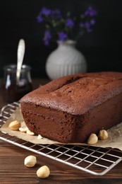 Delicious chocolate sponge cake and nuts on wooden table, closeup