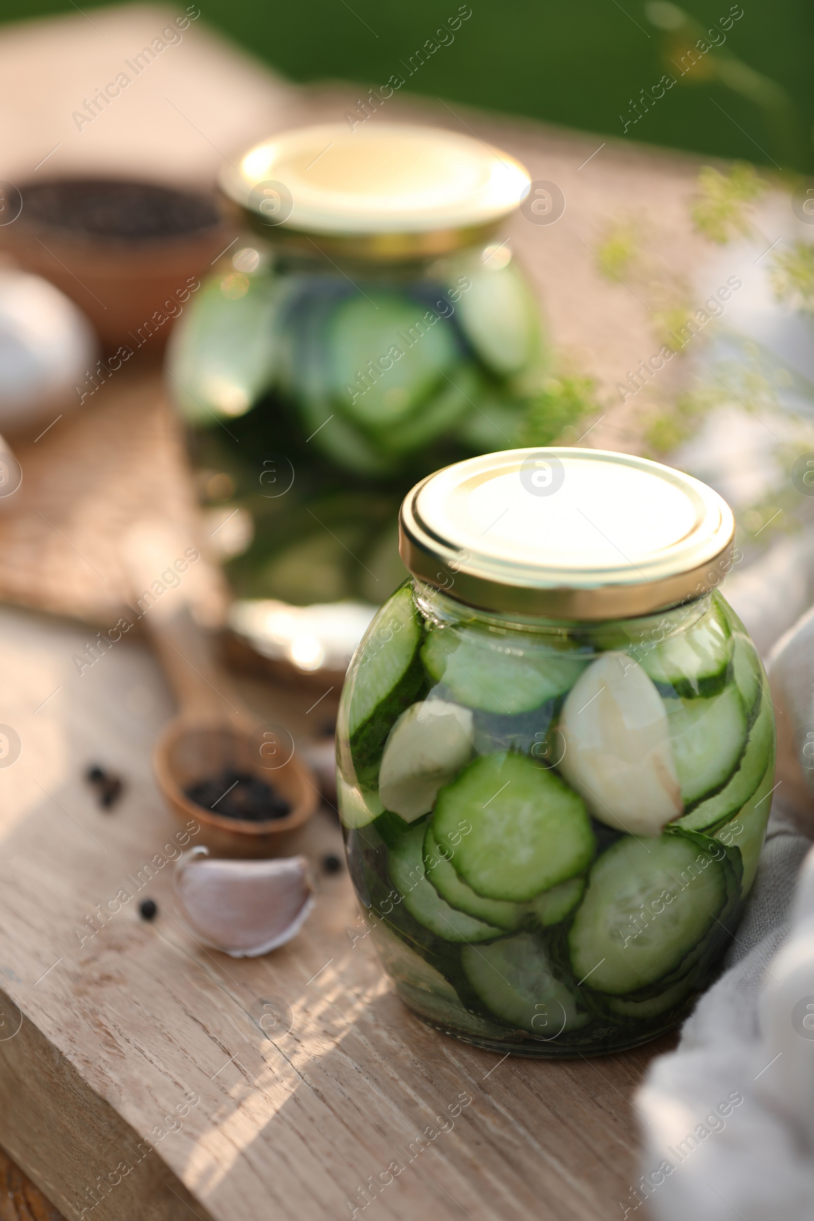 Photo of Jar of delicious pickled cucumbers on wooden table, closeup