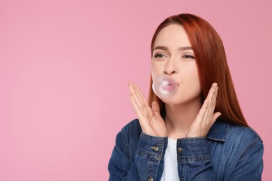 Portrait of beautiful woman blowing bubble gum on pink background. Space for text