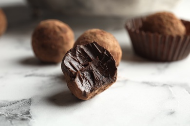 Photo of Tasty raw chocolate truffles on marble table, closeup
