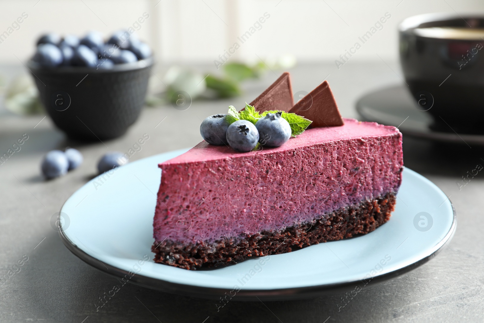 Photo of Plate with piece of tasty blueberry cake on gray table