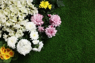 Photo of Different beautiful flowers on green grass, flat lay. Space for text