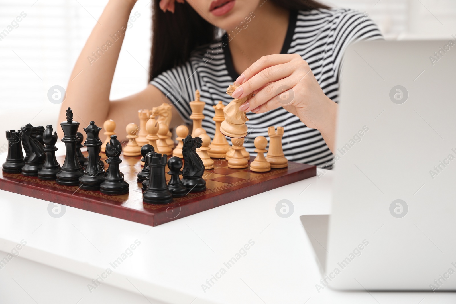 Photo of Woman playing chess with partner through online video chat at home, closeup