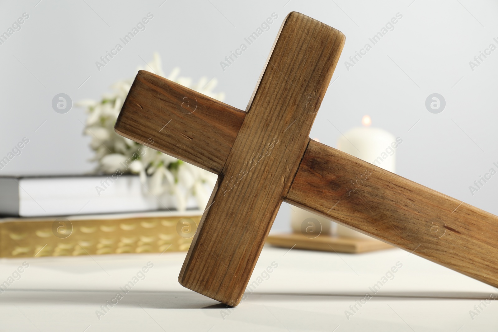 Photo of Wooden Christian cross on white table, closeup