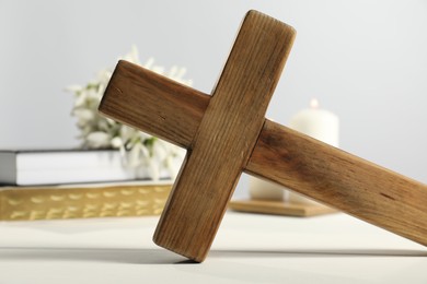 Photo of Wooden Christian cross on white table, closeup