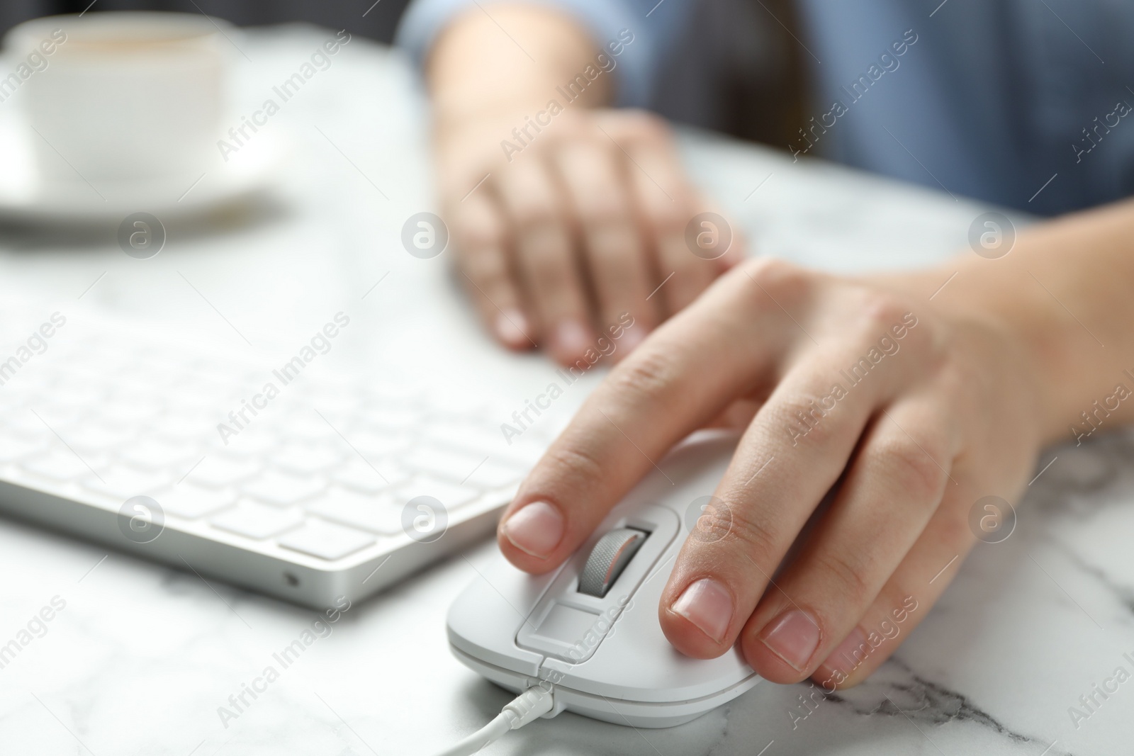 Photo of Woman using wired computer mouse at marble table, closeup