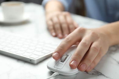 Photo of Woman using wired computer mouse at marble table, closeup