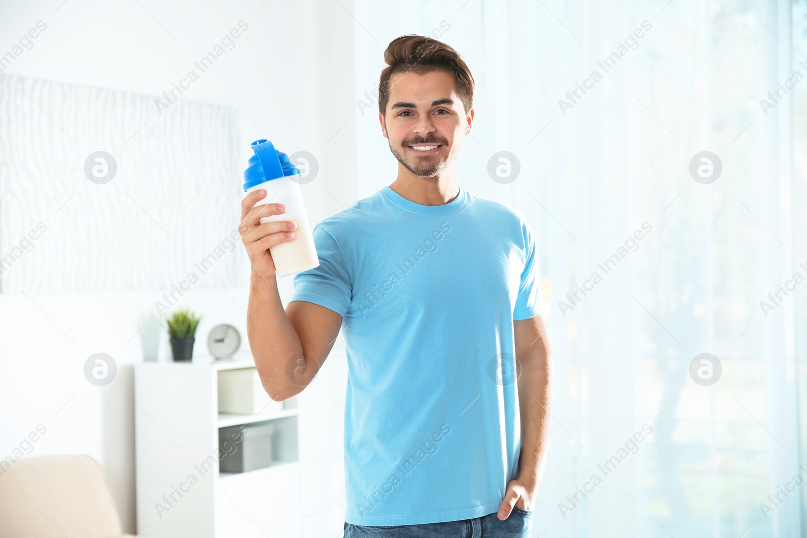 Photo of Young man with bottle of protein shake at home