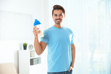 Photo of Young man with bottle of protein shake at home