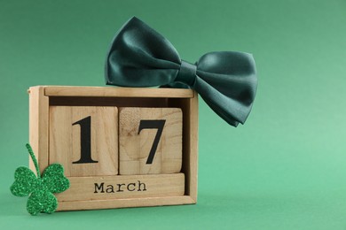 Photo of St. Patrick's day - 17th of March. Block calendar, bowtie and clover leaf on green background