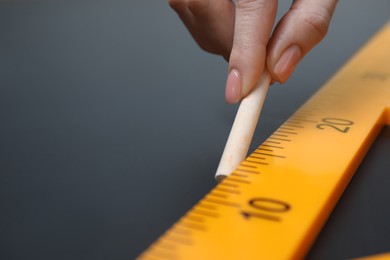 Photo of Woman drawing with chalk and ruler on blackboard, closeup. Space for text