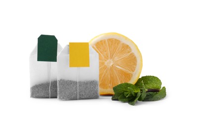 Photo of New tea bags with labels, lemon and mint on white background