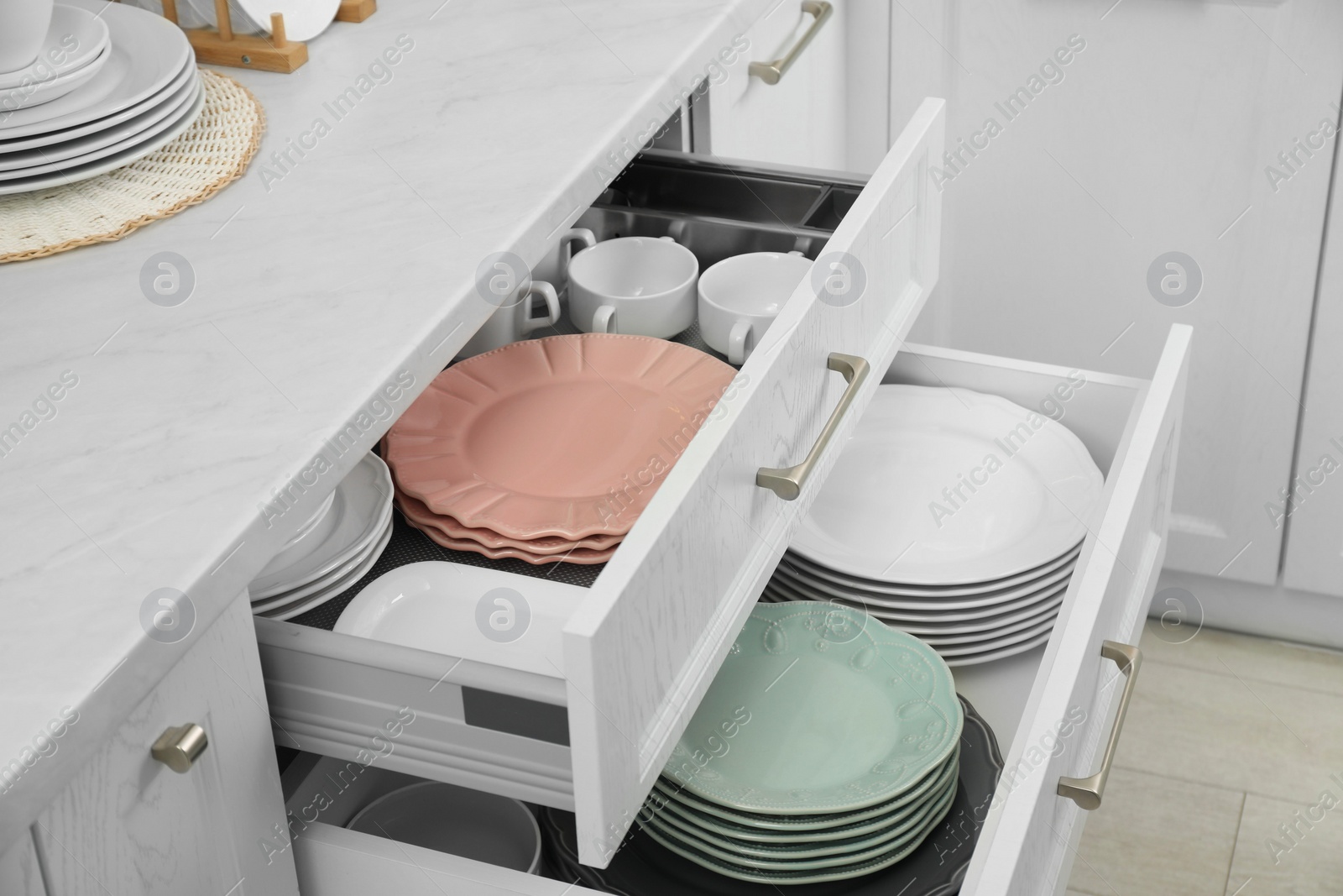 Photo of Clean plates and bowls in drawers indoors