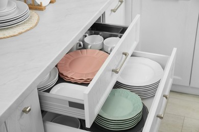 Photo of Clean plates and bowls in drawers indoors