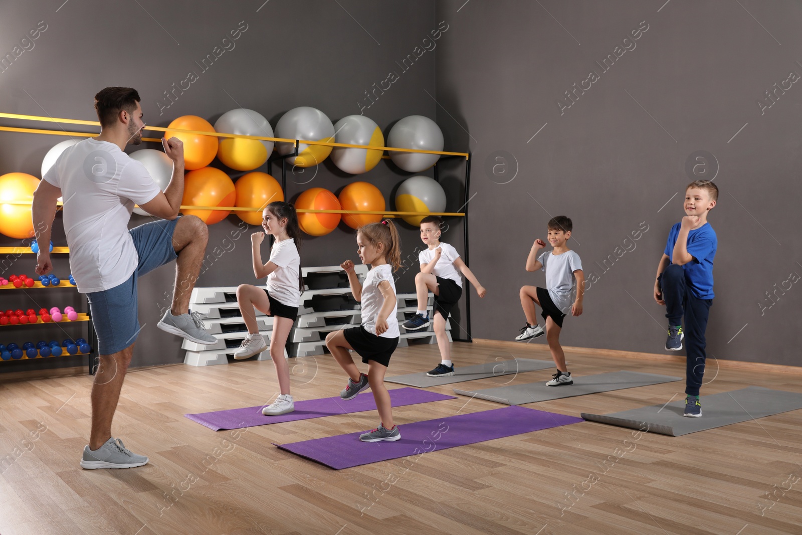 Photo of Cute little children and trainer doing physical exercise in school gym. Healthy lifestyle