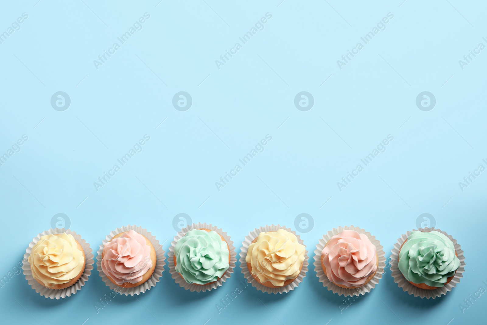 Photo of Flat lay composition with delicious cupcakes on color background, space for text