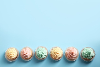 Photo of Flat lay composition with delicious cupcakes on color background, space for text