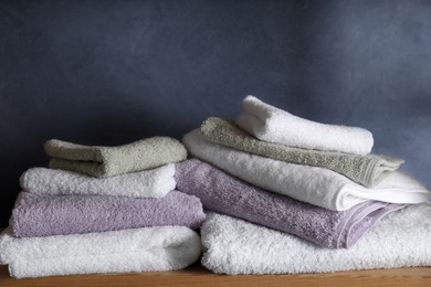 Photo of Stacked soft towels on wooden shelf indoors