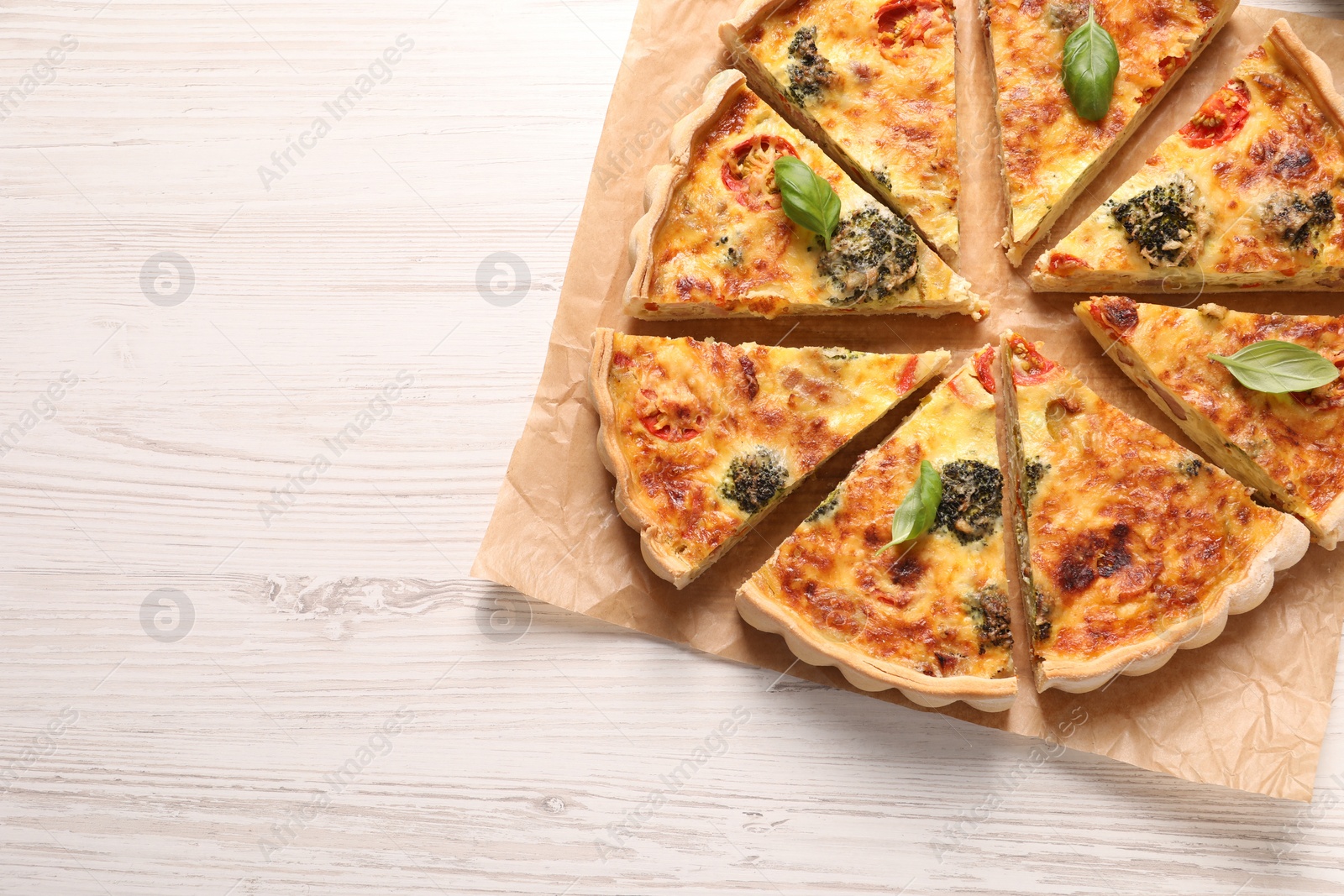 Photo of Delicious homemade vegetable quiche on white wooden table, flat lay. Space for text