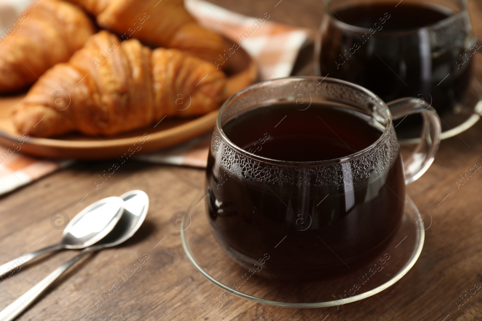 Photo of Hot coffee in glass cup on wooden table, closeup