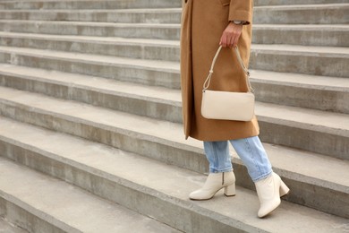 Photo of Stylish woman with trendy beige bag on stairs outdoors, closeup