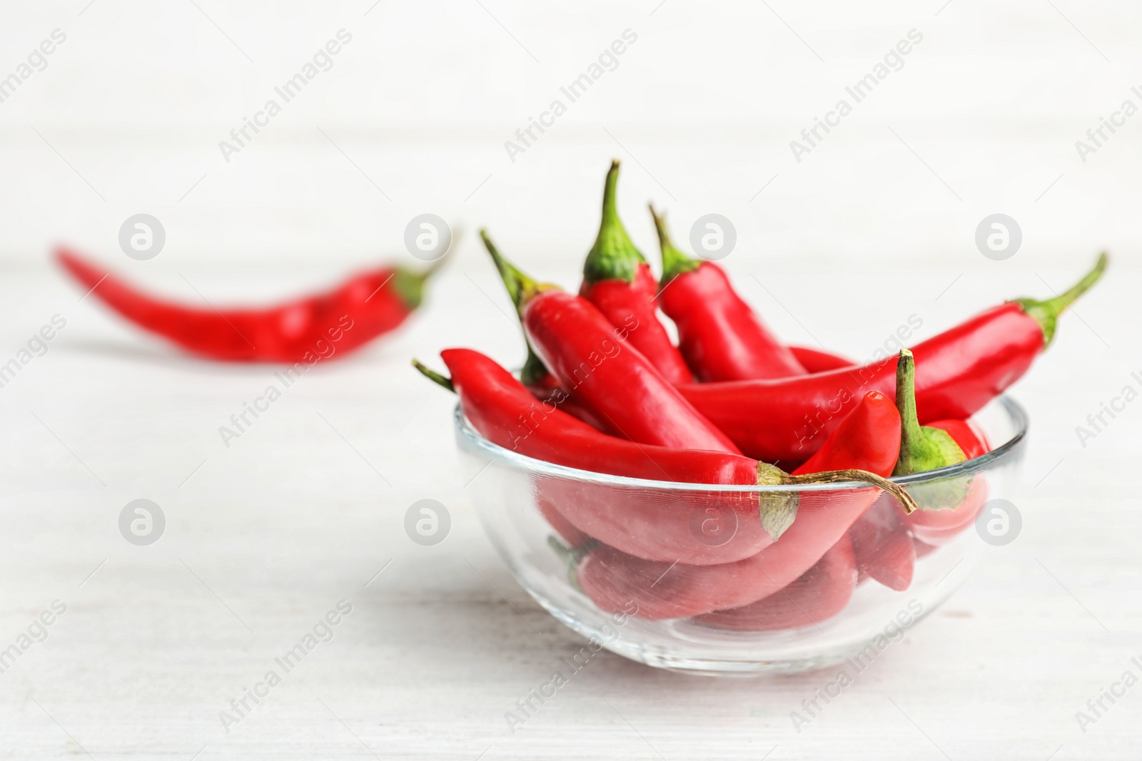 Photo of Bowl with red chili peppers on wooden table