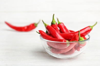 Photo of Bowl with red chili peppers on wooden table