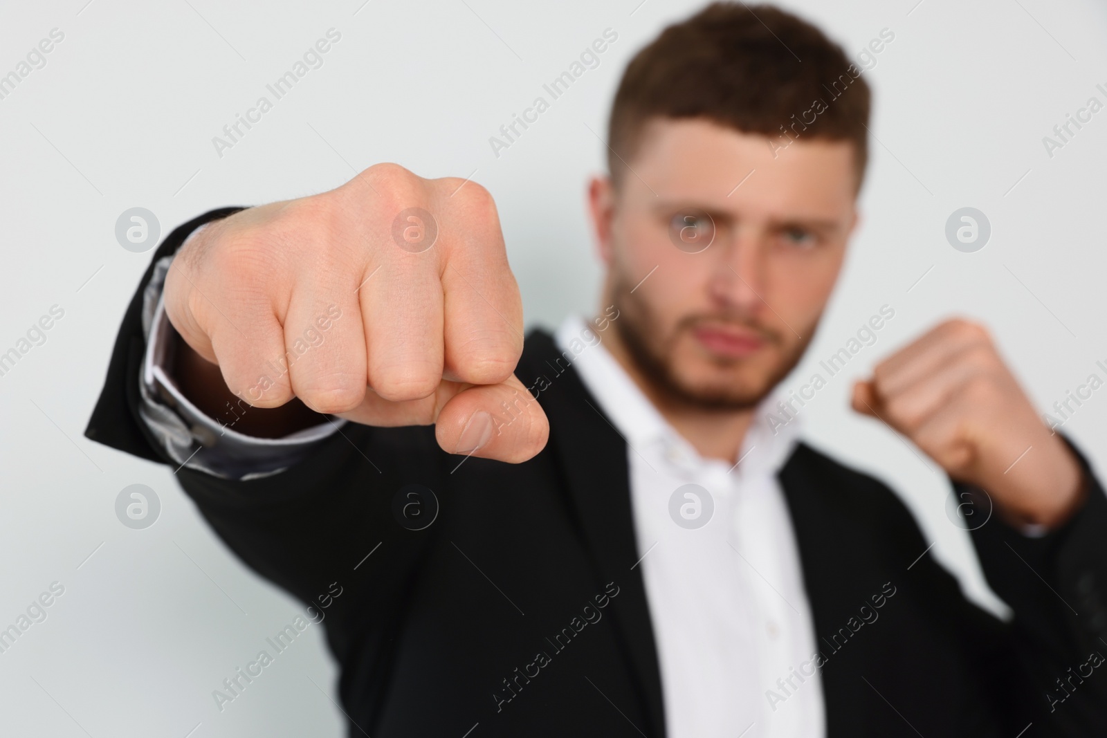 Photo of Young man ready to fight against white background, focus on hand. Space for text