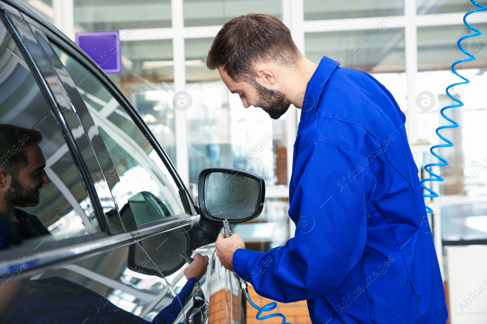 Photo of Worker using gun for auto cleaning at car wash