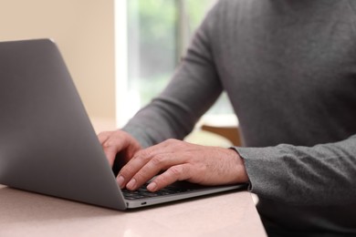 Photo of Man working on laptop at table in cafe, closeup