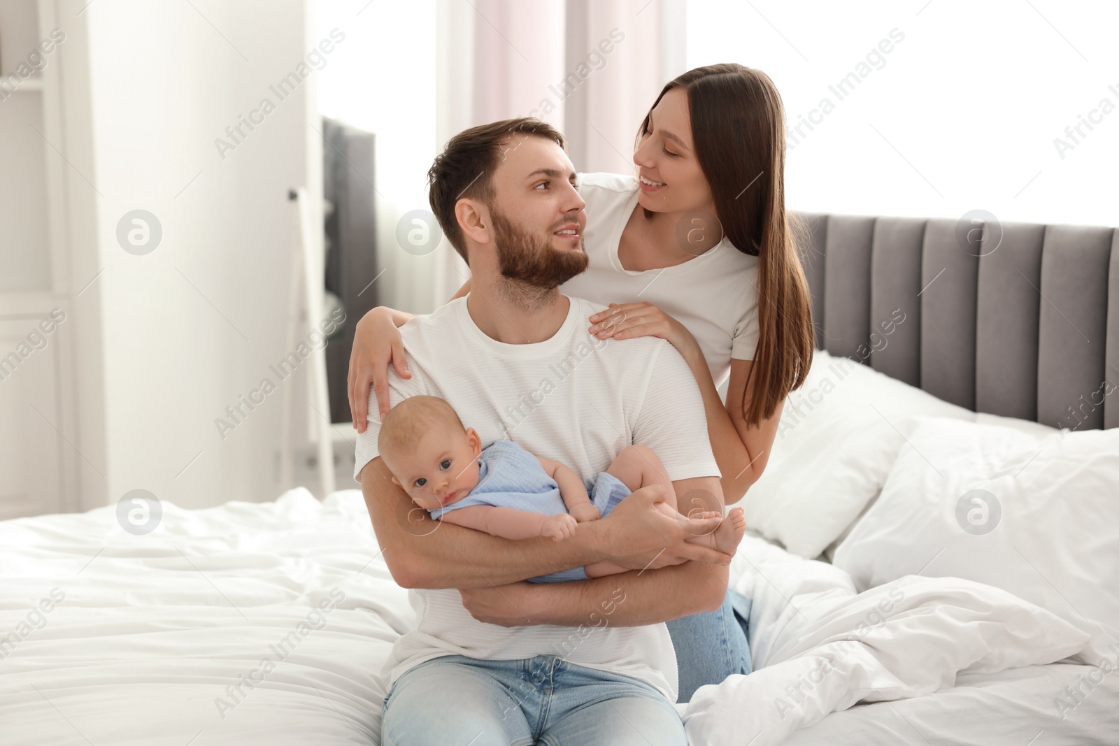 Photo of Happy family. Parents with their cute baby on bed indoors