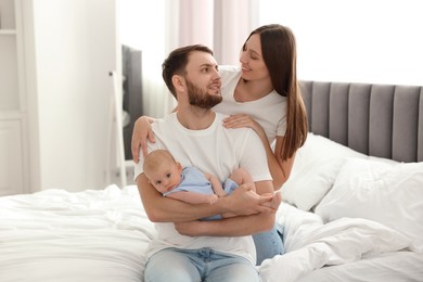 Happy family. Parents with their cute baby on bed indoors