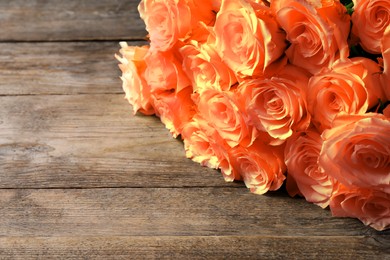 Image of Beautiful bouquet of orange roses on wooden table, closeup. Space for text