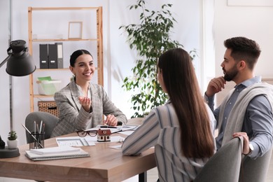 Photo of Real estate agent working with young couple in office. Mortgage concept