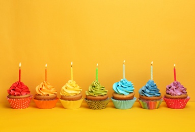 Photo of Birthday cupcakes with candles on color background