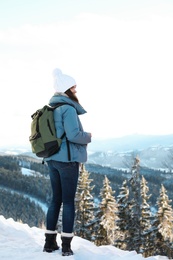 Woman with backpack enjoying mountain view during winter vacation